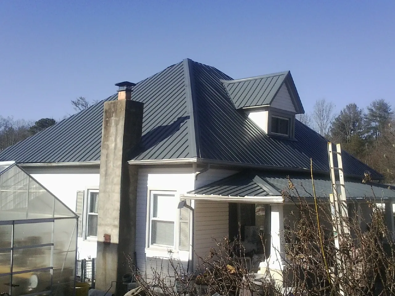 Dark blue standing seam metal roof on a white farmhouse with dormer — Slate & Tile Roof Repair by Roofing Brothers in Bell Buckle