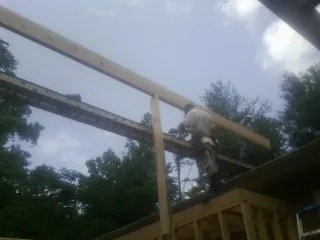 Carpenter setting a ridge beam over a new addition frame — Ice Dam Removal by Roofing Brothers in Bell Buckle
