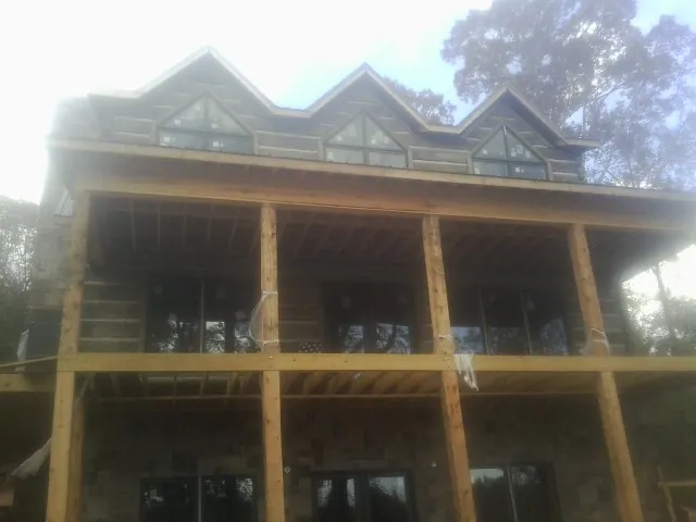 Dormers and porch framing on a large log home under construction — Roof Coating work by our crew in Bell Buckle