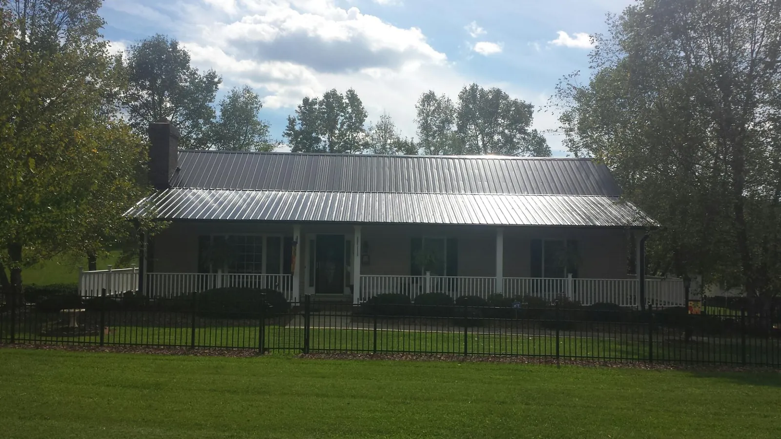 Gray metal roof on a brick ranch with a full width front porch — Gutter Guard Installation work by our crew in Bell Buckle