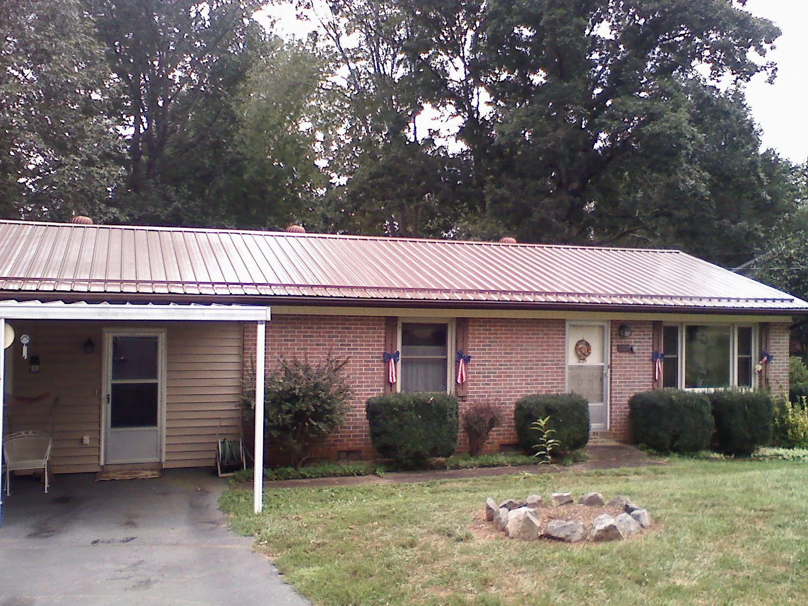 Bronze metal roof and carport on a brick ranch home — Roof Repair work by our crew in Bell Buckle