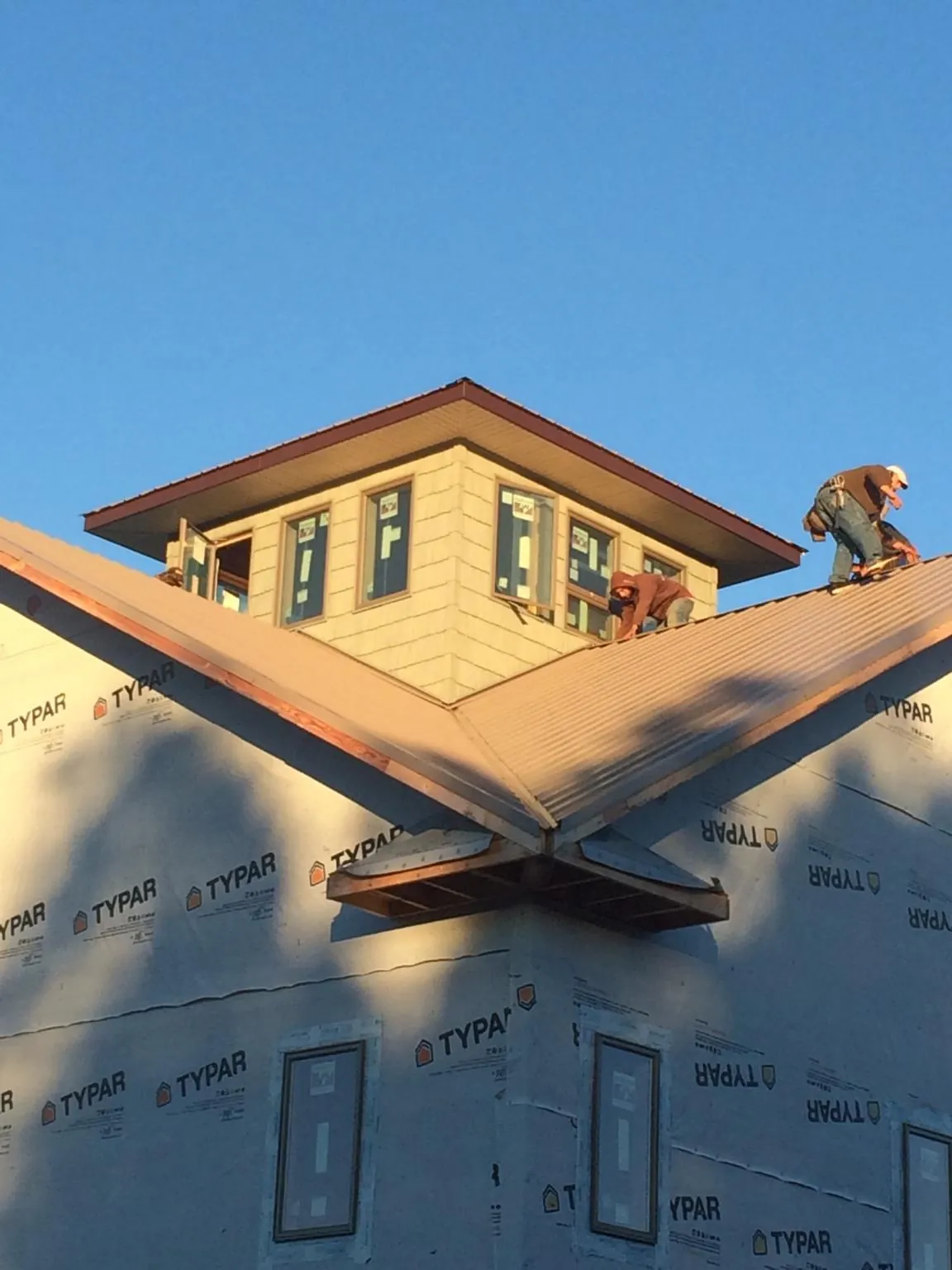 Roofers working around a rooftop cupola on a new metal roof at sunset — Roof Waterproofing in Bell Buckle by Roofing Brothers